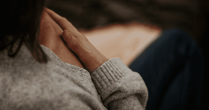 A woman sitting in meditation with her hand on her heart