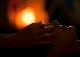 A shamanic healer's hands are gently placed over rthe eyes of a woman during a healing session