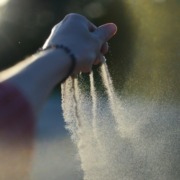 A woman's hand gradually taking her time to let go of sand from her finger tips
