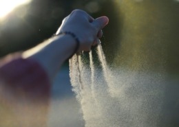 A woman's hand gradually taking her time to let go of sand from her finger tips