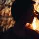 A woman holding her fingers to her third eye with the setting sun shining through her fingers